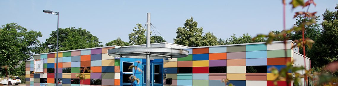 Het gebouw van Kinderopvang De Basis met een gevel van gekleurde panelen