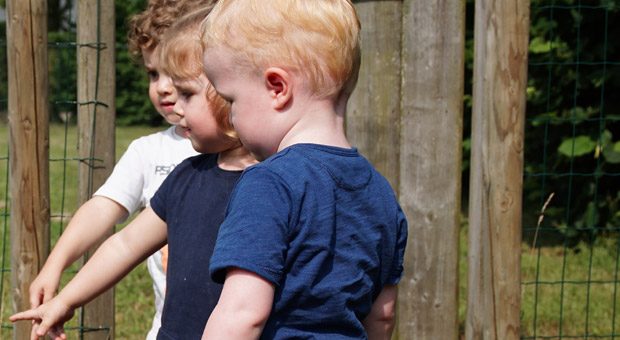 Kinderen bij het hek van de buitenspeelplaats